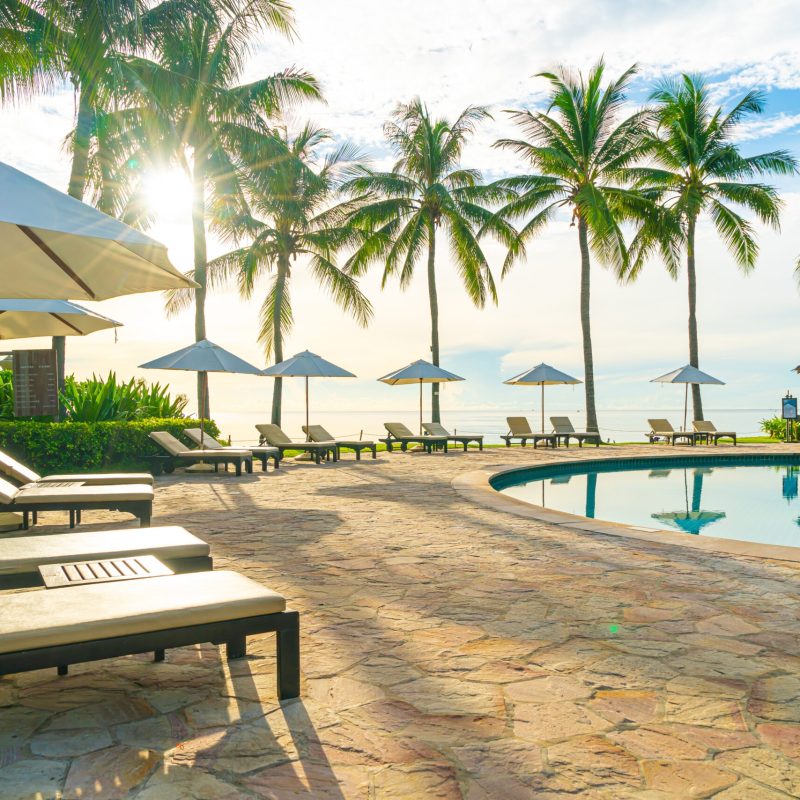 Umbrella and chair around swimming pool in resort hotel for leisure travel and vacation neary sea ocean beach at sunset or sunrise time