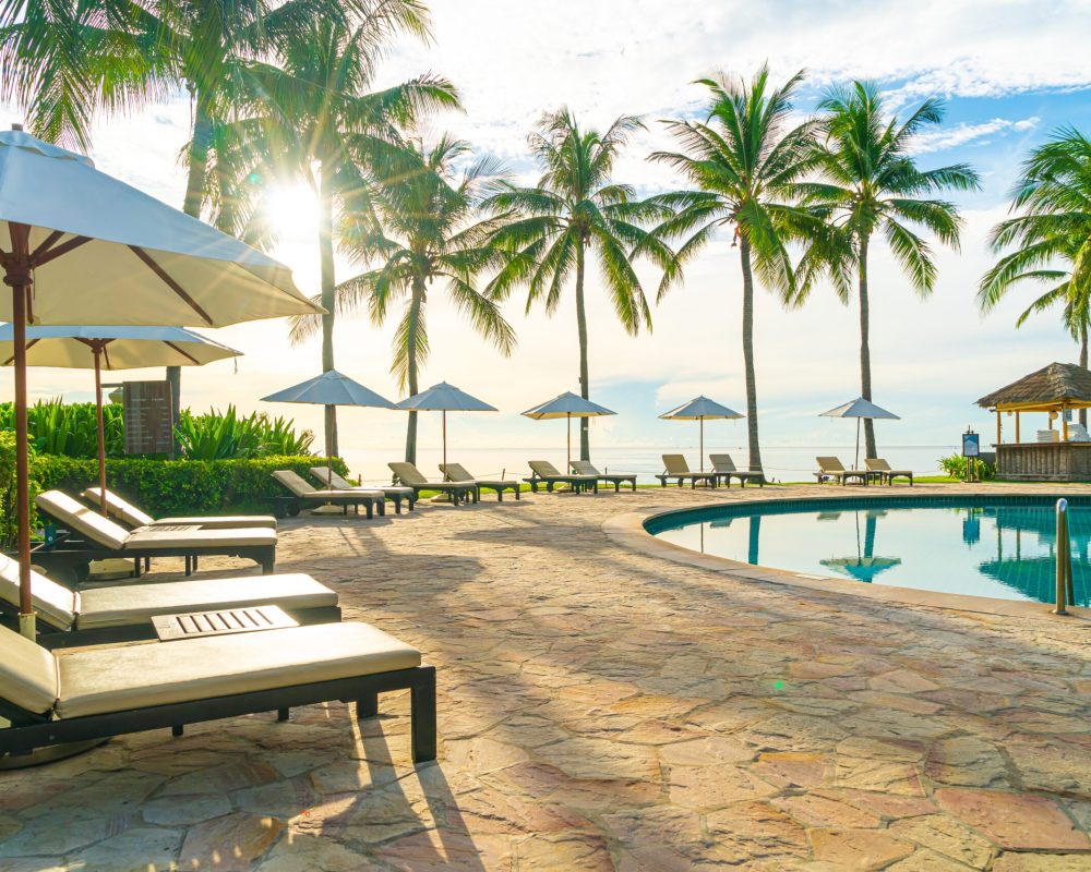 Umbrella and chair around swimming pool in resort hotel for leisure travel and vacation neary sea ocean beach at sunset or sunrise time
